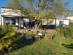 ChâteauthébaudGîtes L'Infinity - 4 Chambres的庭院里放着几把椅子和一棵树