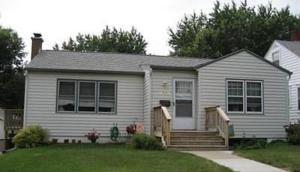 a small house with a porch and stairs in a yard at The Warm & Inviting Place in Sioux Falls