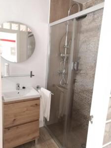 ein Badezimmer mit Dusche, Waschbecken und Spiegel in der Unterkunft Acogedor Apartamento Entero in Arcos de la Frontera