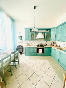 a kitchen with blue cabinets and a table with chairs at JCK Tuscany Apartment in Livorno