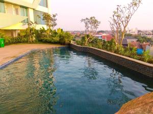 a swimming pool in front of a building at Minimalist Studio Grand Kamala Lagoon Apartment By Travelio in Bekasi