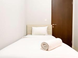 a bed with white sheets and a towel on it at Comfort 2BR at Transpark Juanda Bekasi Timur Apartment By Travelio in Bekasi +21 photos