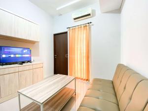 a living room with a couch and a tv at Comfort 2BR at Transpark Juanda Bekasi Timur Apartment By Travelio in Bekasi