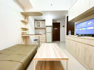 a living room with a couch and a flat screen tv at Comfort 2BR at Transpark Juanda Bekasi Timur Apartment By Travelio in Bekasi
