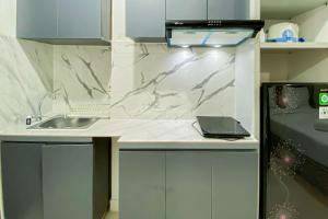 a kitchen with a sink and a laptop on a counter at Comfy and Tidy Studio Transpark Cibubur Apartment By Travelio in Depok