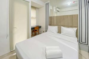 a large white bed in a room with a desk at Comfy and Tidy Studio Transpark Cibubur Apartment By Travelio in Depok +11 photos