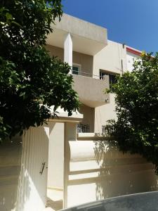 a white building with stairs in front of it at Tiba soliman plage in Nabeul
