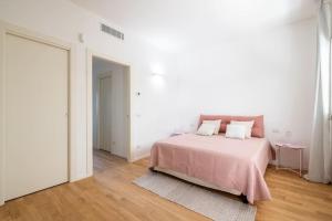 una camera bianca con un letto con una coperta rosa di Dimora Anna - Exclusive Sea Loft a Bari