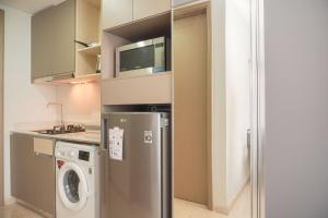 a kitchen with a refrigerator and a washing machine at Minimalist and Nice Studio at Gold Coast Apartment By Travelio in Jakarta
