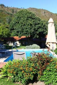 a pool with a umbrella and a table and a chair at As Casinhas de Loureda in Arcos de Valdevez