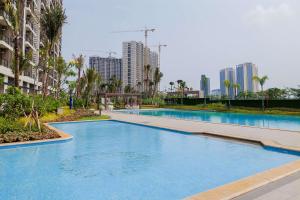 a large swimming pool in a city with tall buildings at Good Designed and Restful Studio Sky House BSD Apartment By Travelio in Tangerang