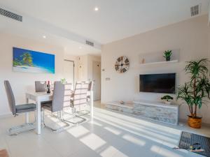 ein Wohnzimmer mit Tisch und Stühlen und einem Fernseher in der Unterkunft Apartment Perla del Sol in Arenales del Sol