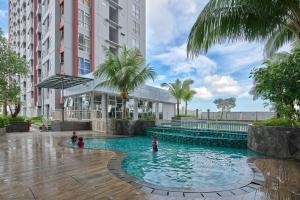 a pool in the middle of a building with people in it at Modern Designed 2BR at Vida View Makassar Apartment By Travelio in Pampang