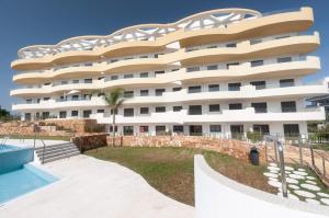 ein großes weißes Gebäude mit einem Garten davor in der Unterkunft Apartment Perla del Sol in Arenales del Sol