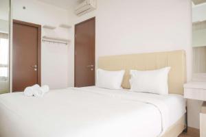 Un dormitorio con una gran cama blanca con toallas. en Minimalist and Homey 1BR M-Town Signature Apartment By Travelio, en Tangerang 16 fotos más