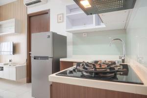 una cocina con estufa horno de arriba junto a una nevera en Minimalist and Homey 1BR M-Town Signature Apartment By Travelio, en Tangerang