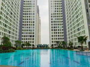 a large swimming pool in the middle of two tall buildings at Best Deal 3BR Apartment M-Town Residence near Summarecon Mall By Travelio in Tangerang