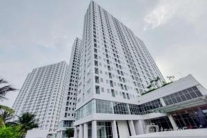 a tall white building with two tall at Homey and Simply 2BR at Serpong Garden Apartment By Travelio in Tangerang
