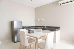 a kitchen with a table and a stainless steel refrigerator at Best Homey and Nice 2BR at Ciputra International Apartment By Travelio in Jakarta