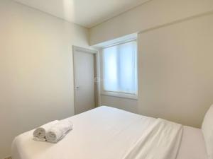 芝卡朗Comfortable and Spacious 3BR Meikarta Apartment By Travelio的白色卧室,配有带毛巾的床