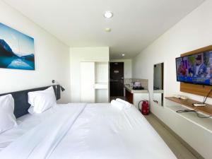 a large white bed in a room with a tv at Enjoy Living Studio at Enviro Apartment By Travelio in Cikarang