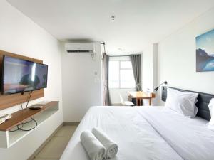 a white bedroom with a large bed and a tv at Enjoy Living Studio at Enviro Apartment By Travelio in Cikarang