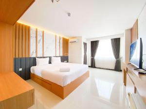 a bedroom with a bed and a flat screen tv at Homey and Strategic Studio (No Kitchen) at Sentraland Semarang Apartment By Travelio in Semarang