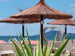 a table with two straw umbrellas on a beach at Miggle-Moo-Sea in Argelès-sur-Mer +6 photos