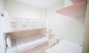 a small white room with pink and white shelves at Best Choice and Cozy Living 2BR at Bale Hinggil Apartment By Travelio in Medokanayu +30 photos