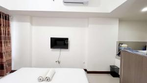 PampangにあるCompact Studio Room Apartment Vida View Makassar By Travelioのベッドと壁にテレビが備わったホテルの部屋