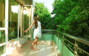 a woman in a white dress standing on a balcony at Perch Arbor-Golf Course Road in Gurgaon