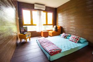 a bedroom with a bed and a chair and a television at Phor Kub Mae Homestay in Damnoen Saduak