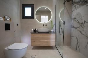 a bathroom with a sink and a toilet and a mirror at Pomaria Boutique Residences in Lefkada