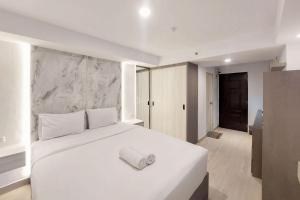 メダンにあるSimply Look Studio Apartment at Mansyur Residence By Travelioのタオルが敷かれた白いベッドのある寝室 +6枚の写真