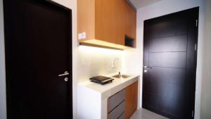 a bathroom with a black door and a sink at Tidy and Cozy Stay Studio Apartment at Suncity Residence By Travelio in Sidoarjo