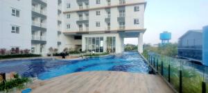 a swimming pool in front of a building at Tidy and Cozy Stay Studio Apartment at Suncity Residence By Travelio in Sidoarjo