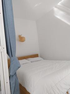 a bedroom with a white bed with a blue curtain at Miggle-Moo-Sea in Argelès-sur-Mer