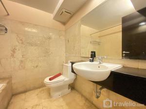 a bathroom with a white toilet and a sink at Simply and Homey 2BR at Braga City Walk Apartment By Travelio in Bandung +2 photos