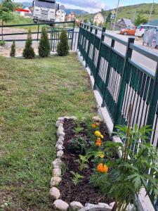 a garden with flowers in a yard next to a fence at Neda Guesthouse in Žabljak