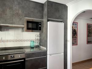 een keuken met een witte koelkast en een magnetron bij Casa La Marina spacious apartment 100m in La Marina