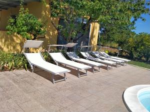 a row of white lounge chairs sitting next to a pool at Villa Cecilia in Scerni