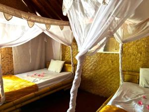 a bedroom with two beds with white curtains at Dessert Point Bungalow in Sekotong