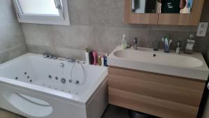 ein Badezimmer mit einer weißen Badewanne und einem Waschbecken in der Unterkunft Villa avec piscine By Platinum Homes- capacité 10 personnes - Heillecourt in Heillecourt