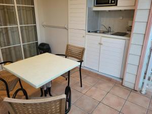 een keuken met een tafel, stoelen en een spoelbak bij Au beau village studio vue nature in Sainte-Luce