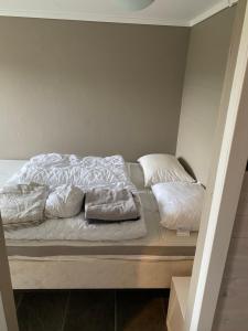 a bed with white sheets and pillows on it at Ingvilds hybelleilighet in Kristiansand