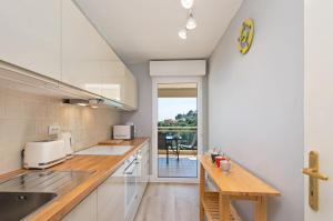 a kitchen with white cabinets and a wooden counter top at BEAUSEJOUR - Splendide 2 pièces - Piscine - Parking - Vue mer in Beausoleil