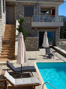 a house with a swimming pool and two chairs and an umbrella at Lavender House 1 - Agios Nikitas in Agios Nikitas