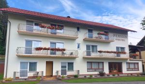 a large white building with flowers on balconies at Pension Hribernig in Sankt Primus am Turnersee