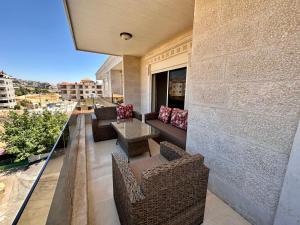 a balcony with chairs and a couch on a building at Ksara Zahle - Luxurious two bedroom apartment in Zahlé