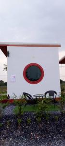 een wit gebouw met een rood raam en twee stoelen bij จันทร์ทิพย์คคำชะโนด 2 เฟท 2 in Ban Dung